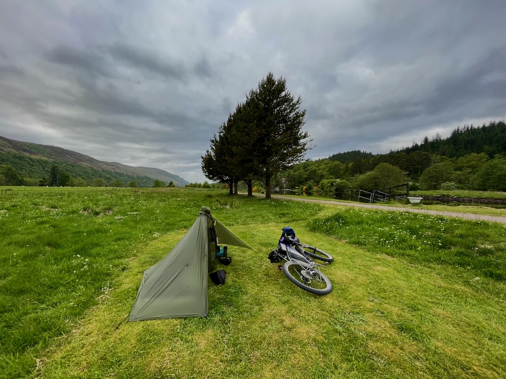bike laying next to a small tent in a grassy plot